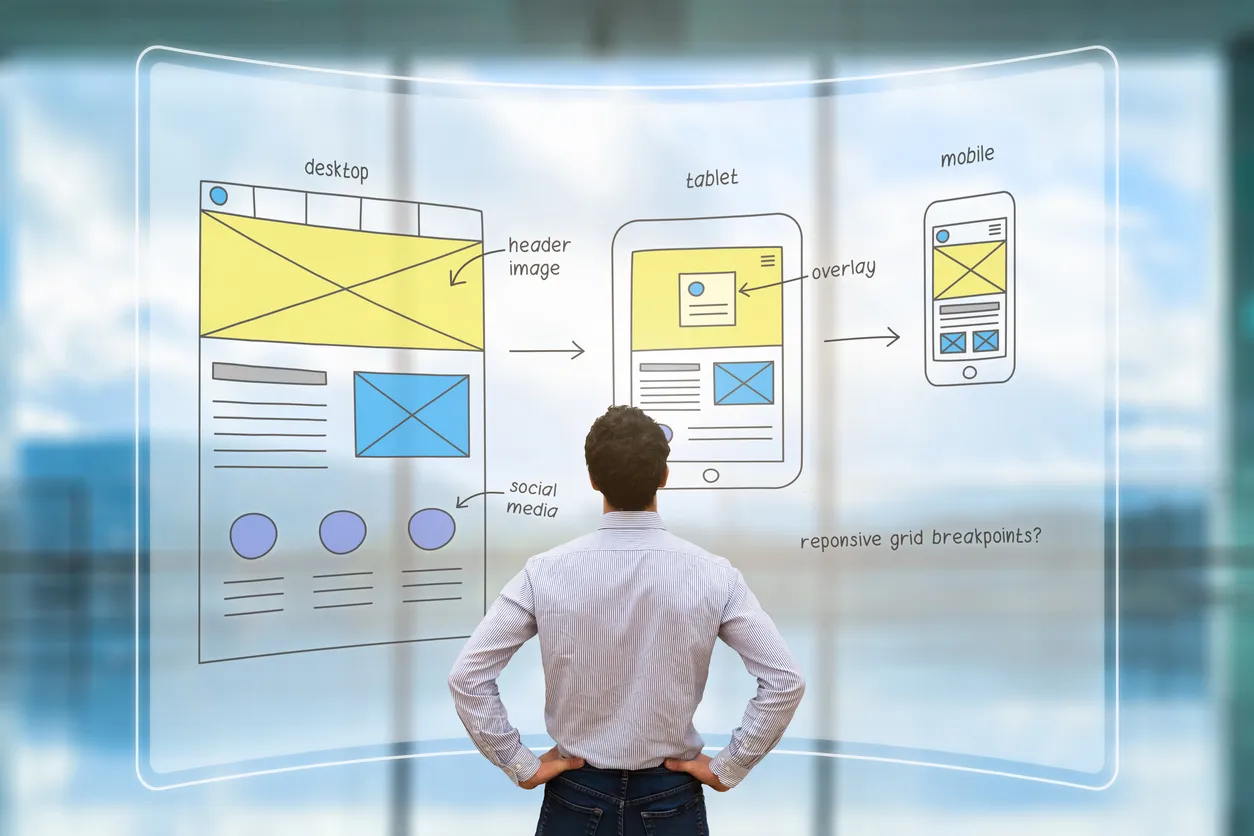 Ein Mensch steht vor einem AR-Bildschirm mit UI/UX Wireframe Layouts die responsives Design zeigen.